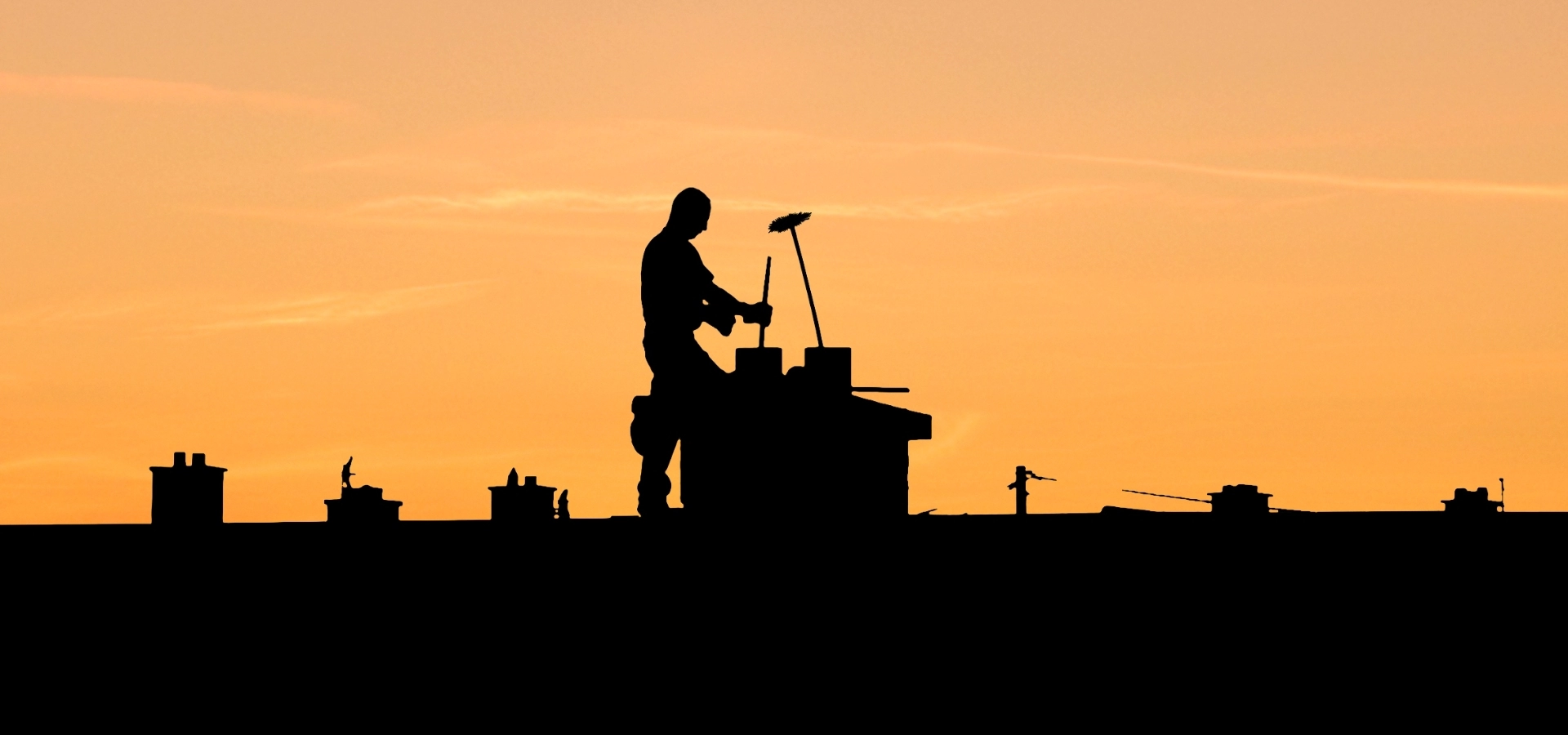 Kominiarz na dachu podczas zachodu słońca
